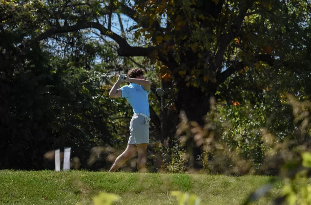 MNU Student at a golf tournament swinging a golf club